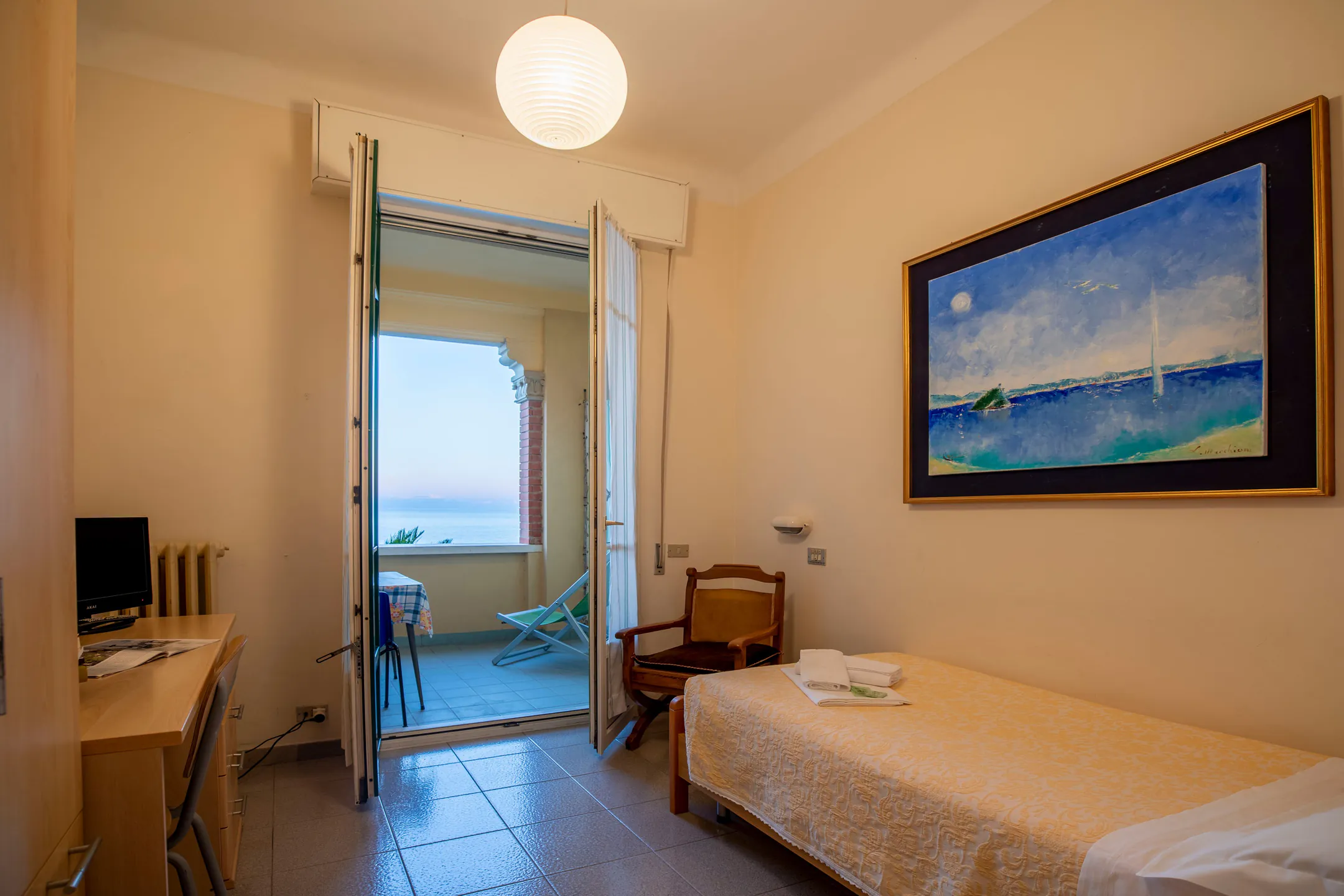 Single room with a desk and a French window open to the sea