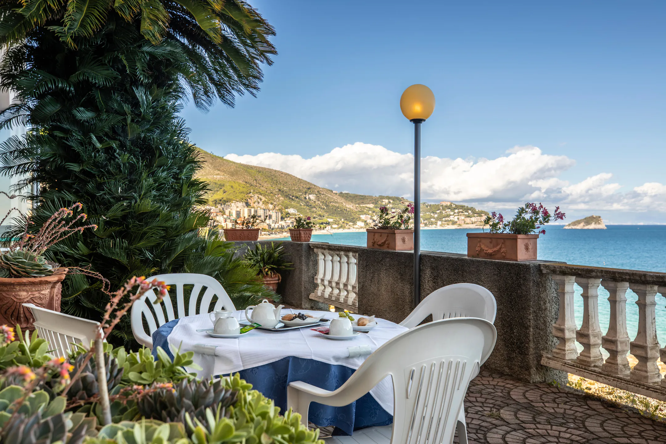Breakfast table on the terrace with a balustrade and a view of the bay