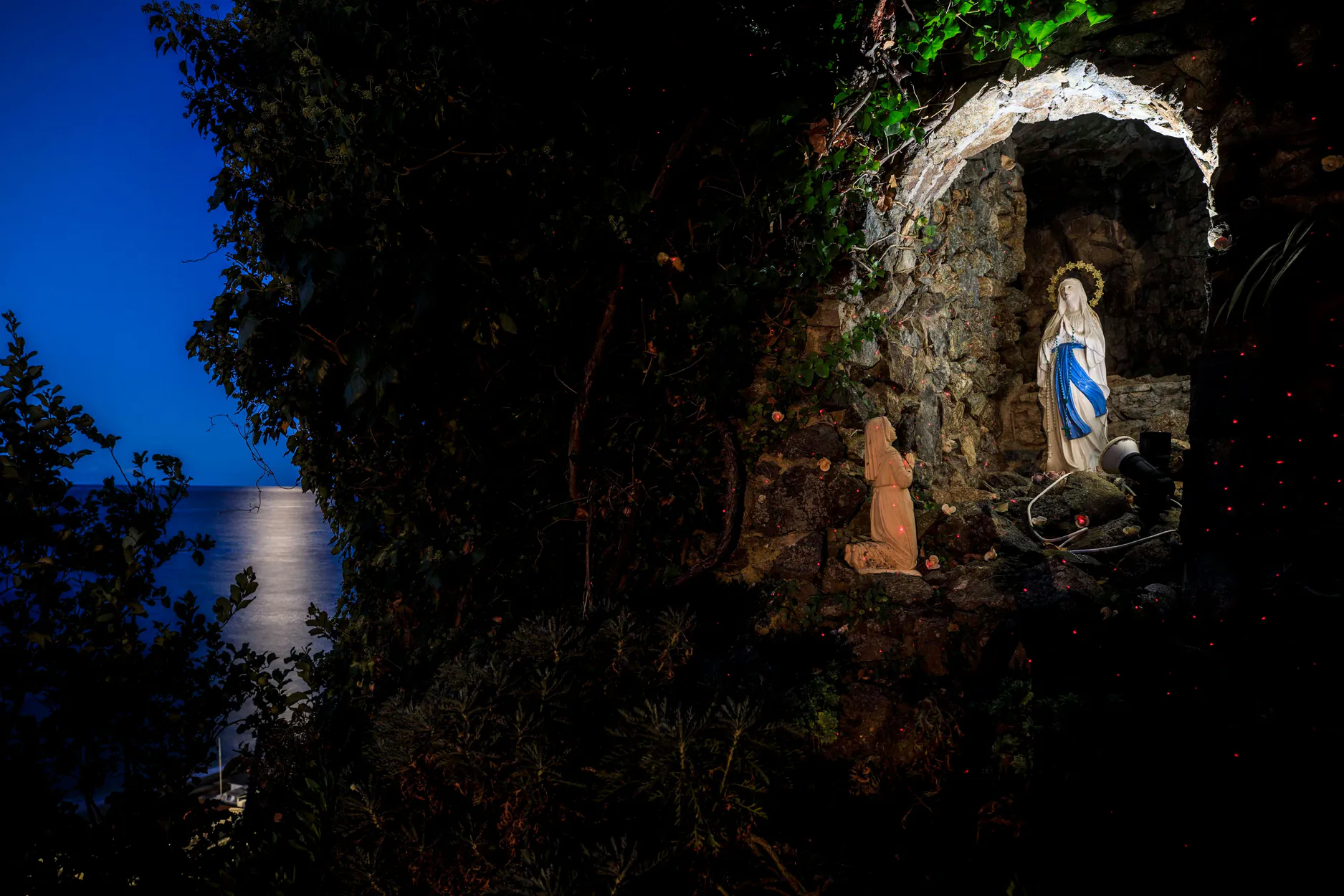 La statua della Madonna di Lourdes nella grotta del parco, illuminata di notte