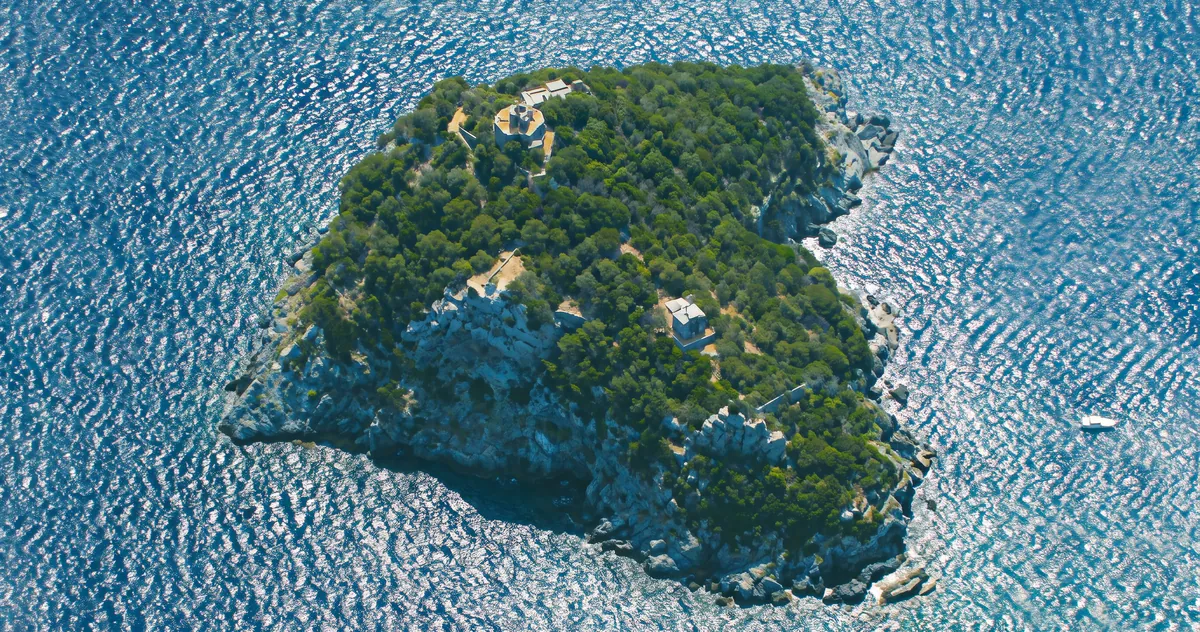 L’Isola di Bergeggi vista dall’alto, coperta di macchia mediterranea in mezzo al mare