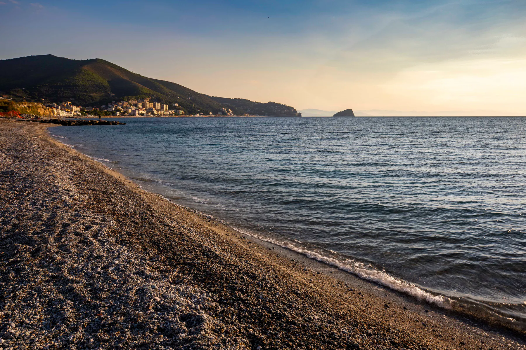 Spiaggia di ciottoli lungo la costa al tramonto